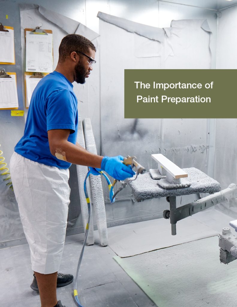 A worker does paint preparation on a piece of wood.