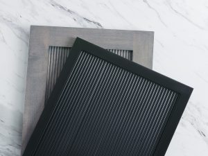 A black reeded panel laying on top of a brown/gray reeded panel. 