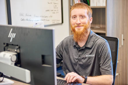 A young man sitting at a desk typing on a keyboard.