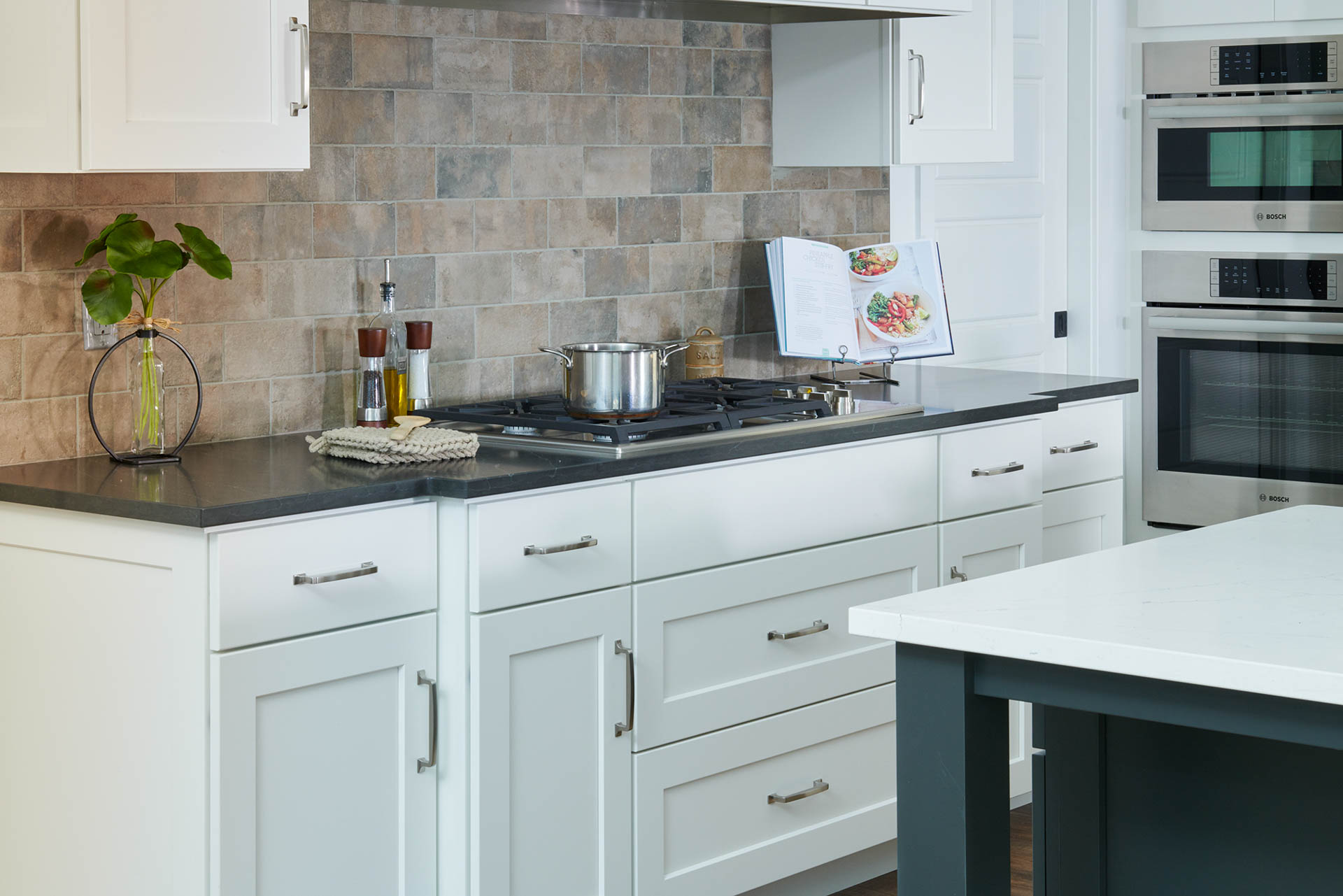 A beautiful while kitchen showing a stovetop cooking area.