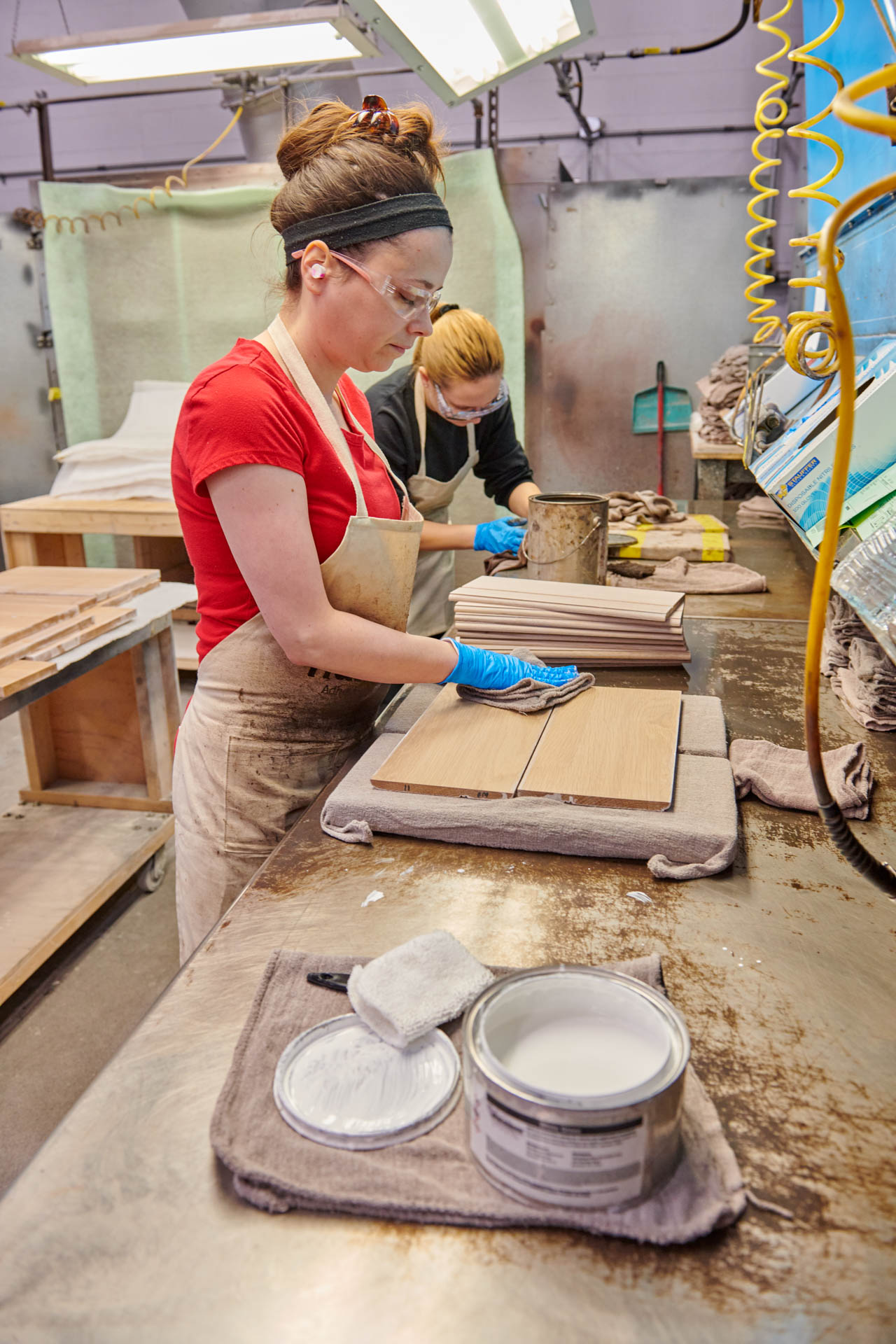A woman wiping stain on a wooden door.