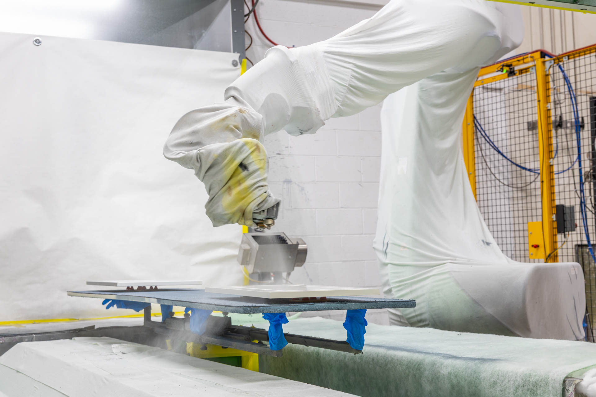 A paint spraying robot spraying white paint on a door.