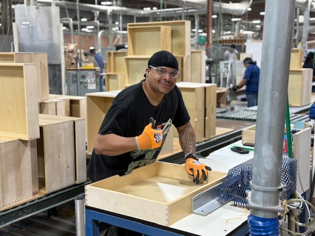 A man giving a thumbs up while assembly a wooden drawer box.