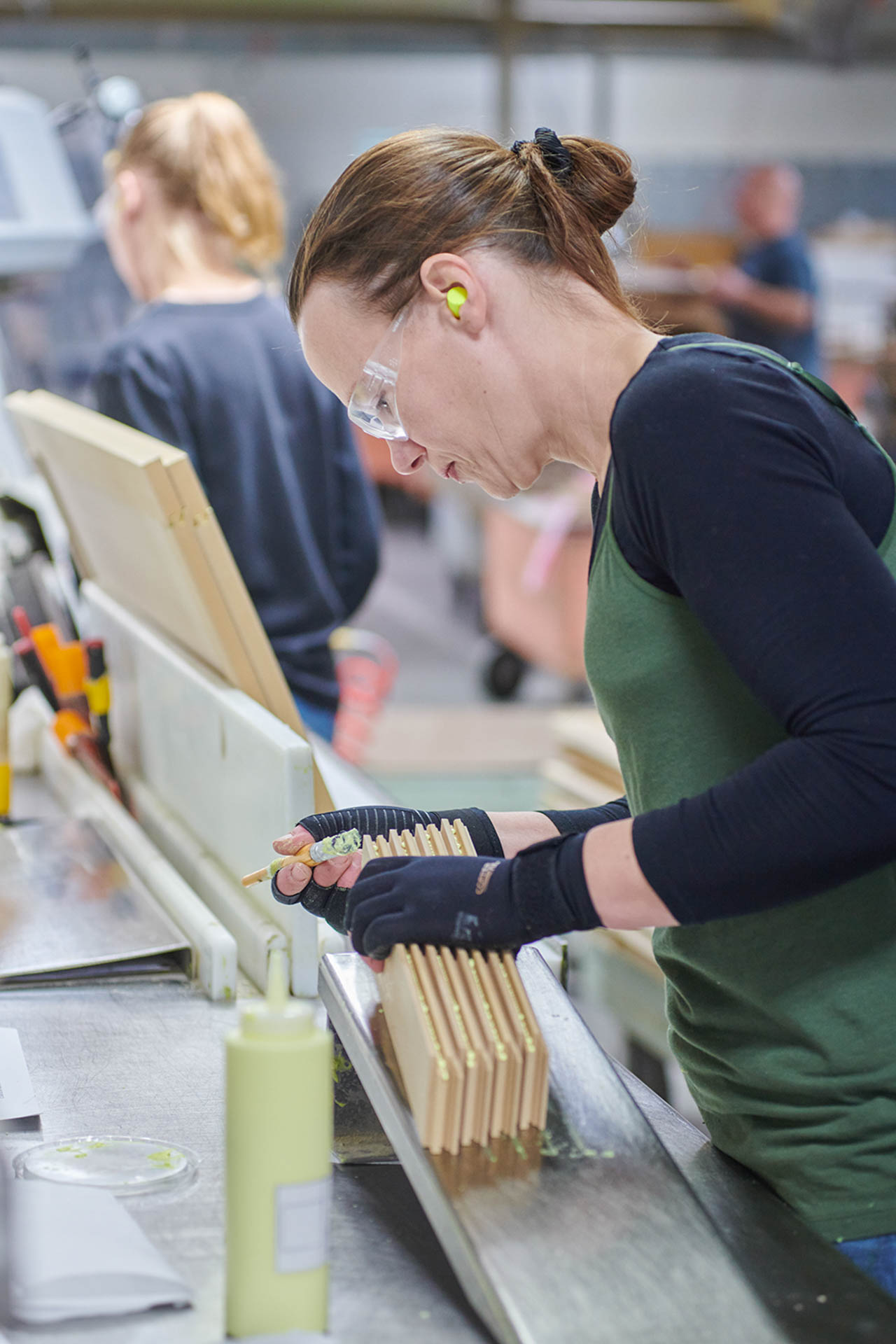 A woman wiping glue on wood framing pieces.